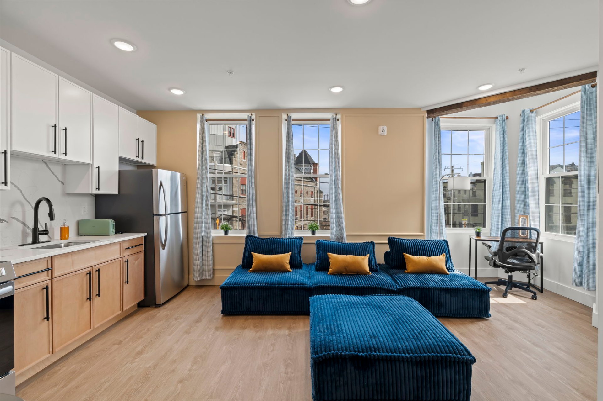 Bright living room and kitchen with city-view windows and blue sectional