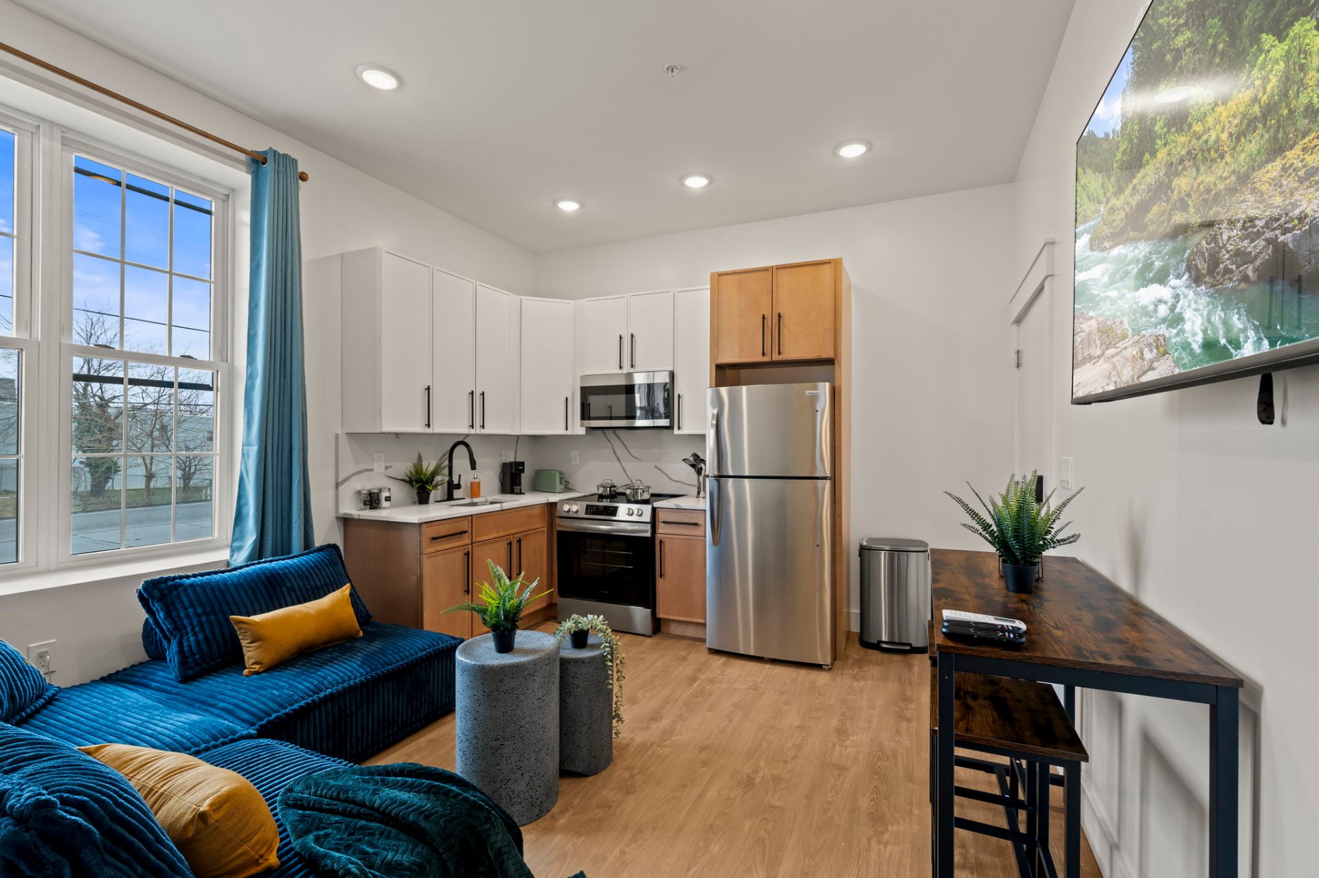 Compact studio with blue sectional and modern kitchen