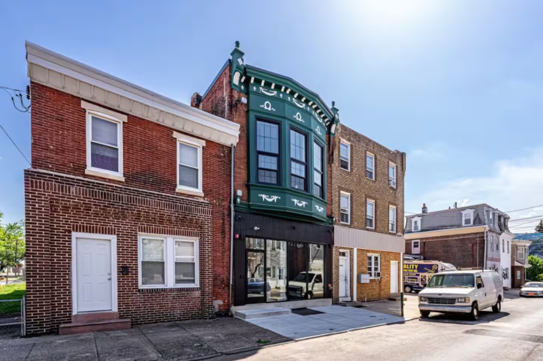 Green bay-window storefront from a side street angle