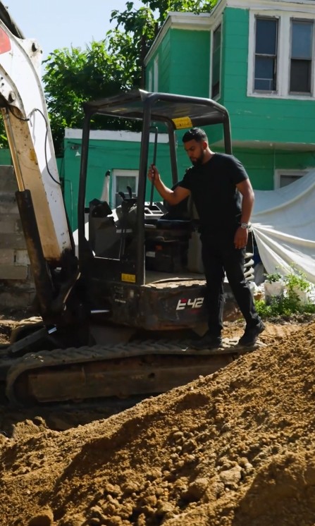 On-site excavation with mini excavator behind a Burg Properties building