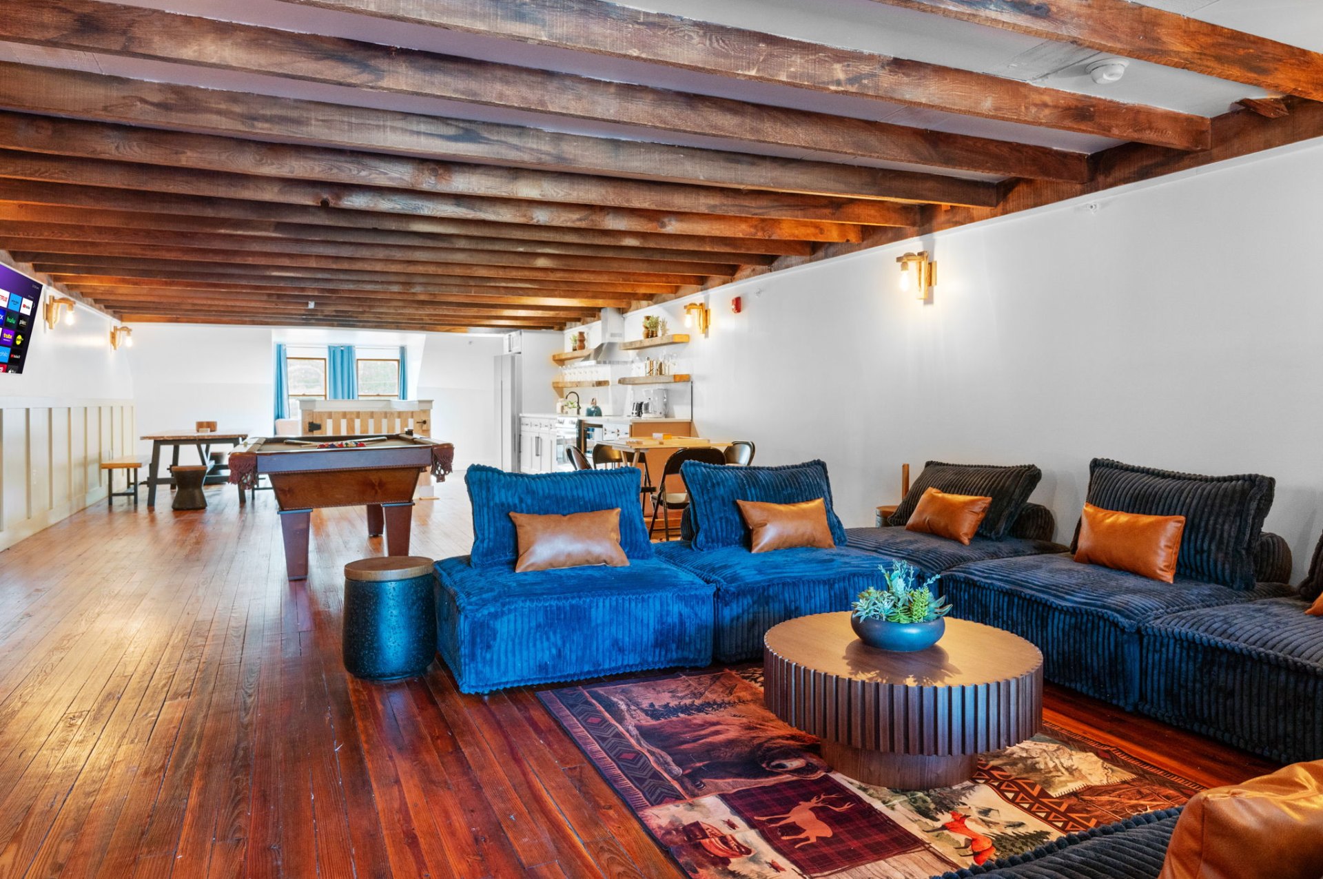 Rustic upstairs lounge with wood-beam ceiling and pool table